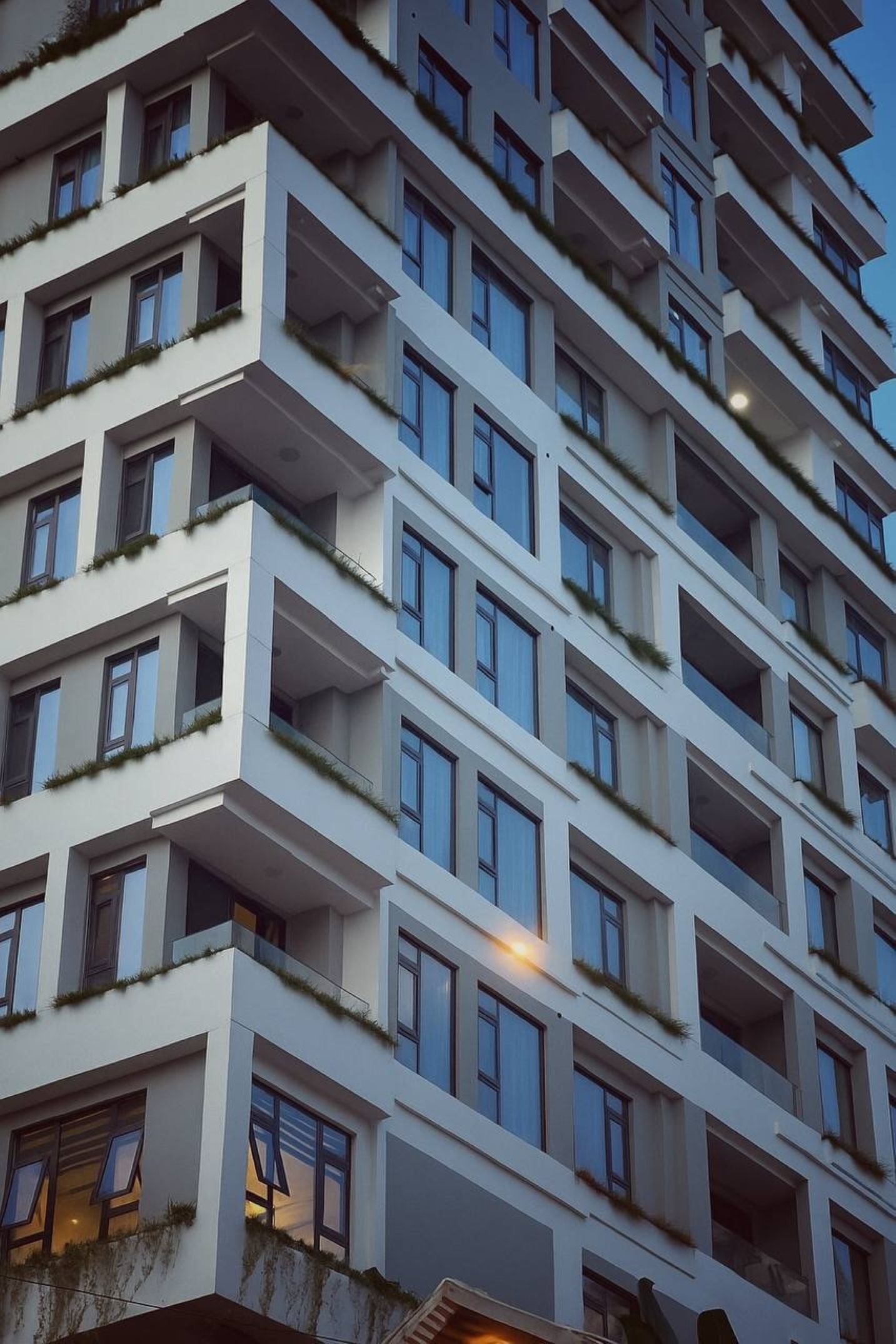 Un edificio de varios pisos con balcones, ventanas amplias y un diseño arquitectónico moderno.