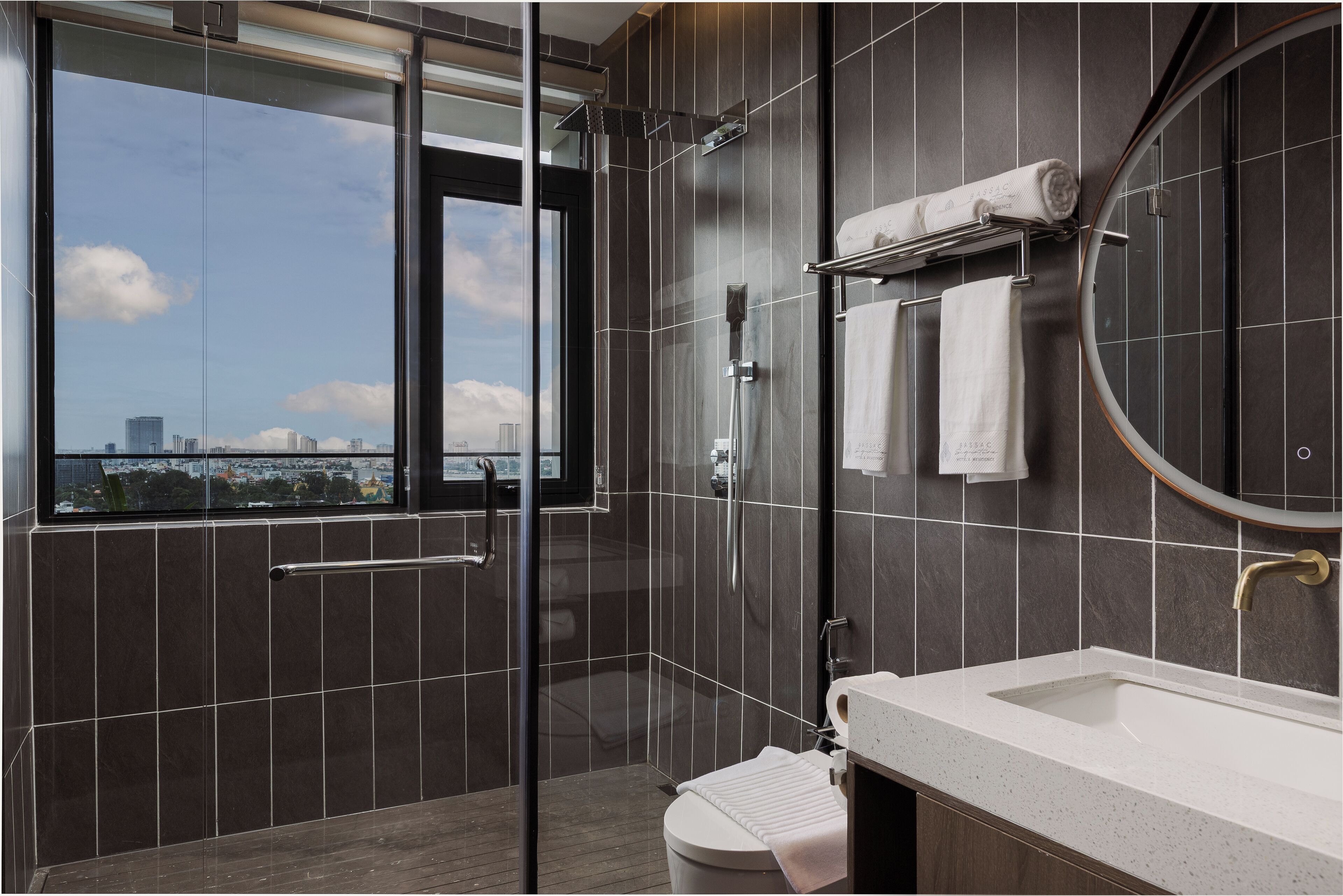 Un baño moderno con ducha de vidrio, inodoro, lavamanos y un espejo grande.