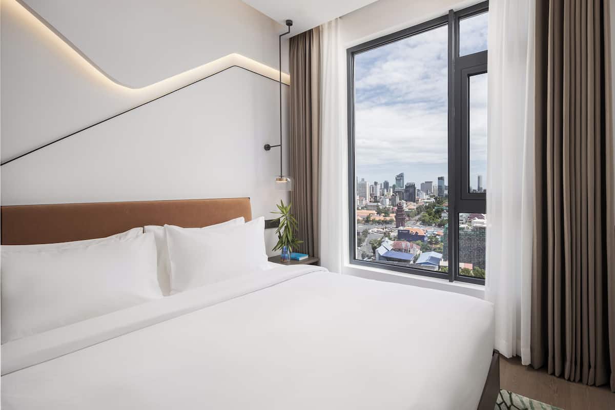 Quarto de hotel moderno com uma cama grande, vista para a cidade e design minimalista.