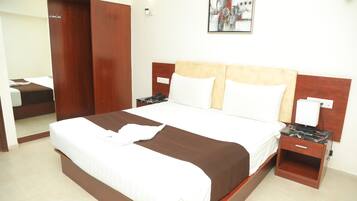 A hotel room with a large bed, wooden headboard, two bedside tables, a nightstand, a wardrobe, and a painting on the wall.