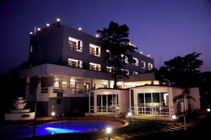 Um hotel moderno com piscina, várias varandas e fachada bem iluminada.