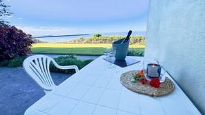 A table set for two with a view of the sea, a candle, and a drink.