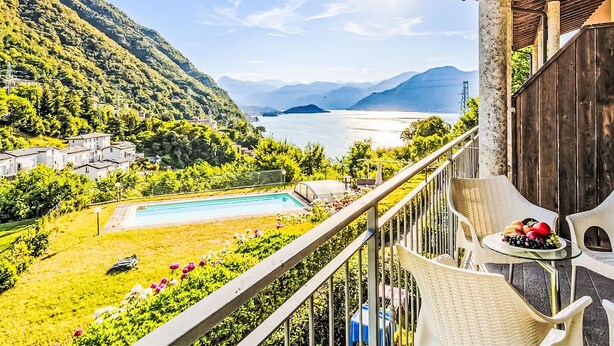 Un balcon avec vue sur un lac, une piscine et un paysage montagneux.
