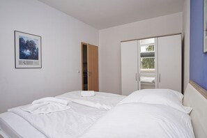 Un dormitorio con cama, armario y puerta que da a un balcón.