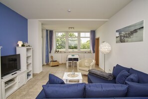 A living room with a TV, sofa, and dining area. - Fantastic ocean view from the balcony, pool, and sauna - Villa Bergfrieden (Göhren)