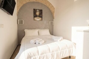 Ein Schlafzimmer mit einem Bett, einem Bild über dem Bett und einem Fernseher an der Wand.