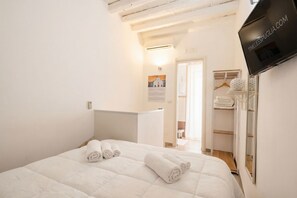 Une chambre d’hôtel comprenant un lit, une télévision, une armoire et une porte donnant sur une salle de bain.