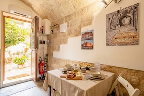 Un coin repas avec une table dressée pour deux personnes, un extincteur et une vue sur l’extérieur.
