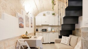 A cozy kitchen with white cabinets, a dining table, and a staircase.