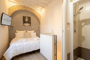 Une chambre à coucher comprenant un lit, une table de chevet, une armoire, une douche et un tableau encadré accroché au mur.