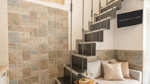 A modern interior with a stone wall, a staircase, a sofa, and a tray with snacks and glasses.