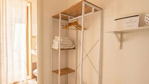 A walk-in closet with a wooden shelf, a hanging rack, and a folded towel rack.