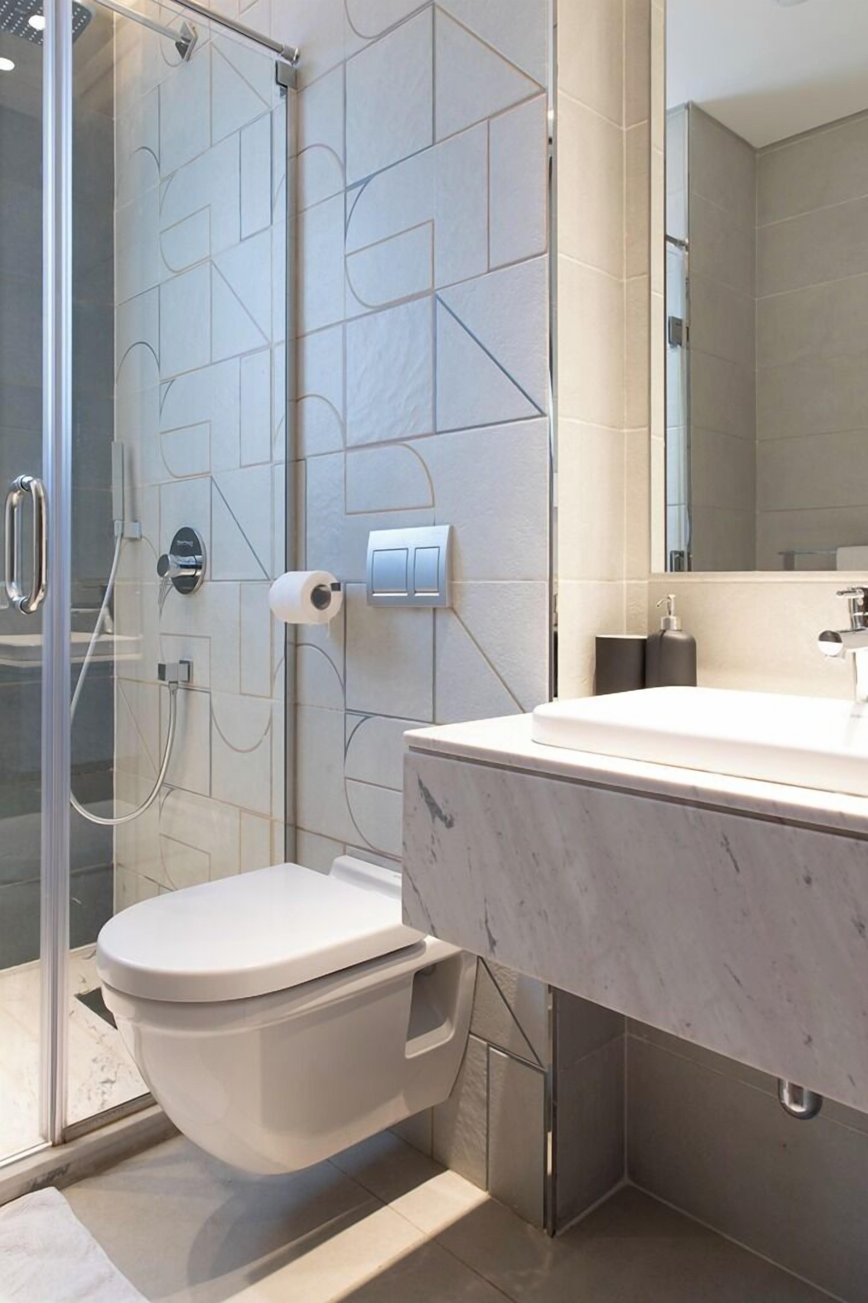 A modern bathroom with a glass shower enclosure, a white toilet, and a marble sink.