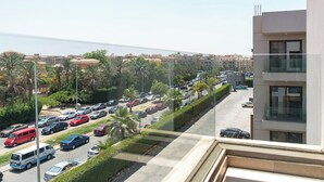 Uitzicht op een parkeerplaats met meerdere auto's en palmbomen, met zicht op een woongebied met gebouwen en een heldere lucht.