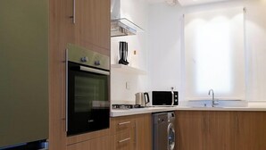 Een moderne keuken met houten kastjes, een roestvrijstalen koelkast, een oven, een magnetron, een vaatwasser en een raam voor natuurlijk licht.