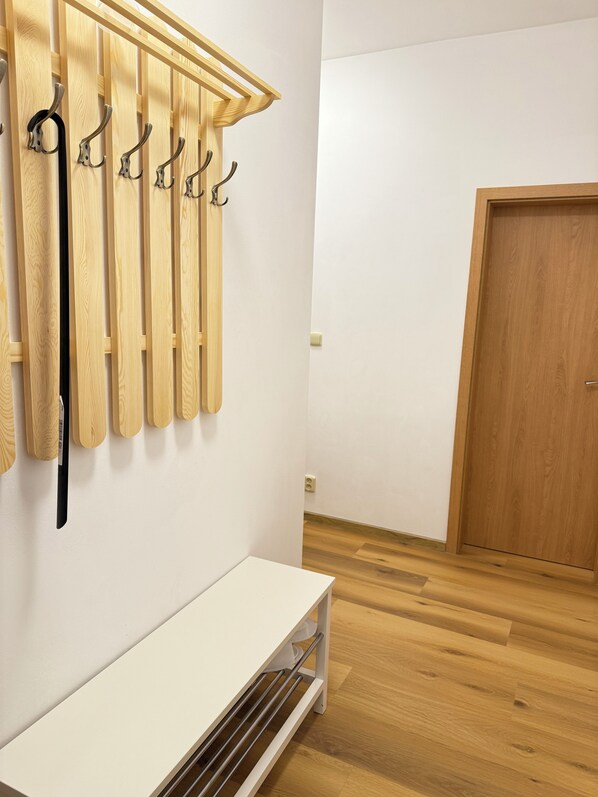 A room with a wooden floor, a white bench, and a wooden door.