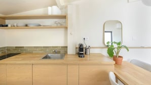 A modern kitchen with a wooden countertop, a sink, and a coffee maker. There is a potted plant on the counter and a mirror above the sink. - Apartment Como - Villa Alcôme (Paris)