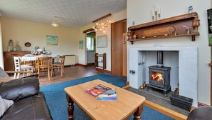 A cozy living room with a fireplace, wooden furniture, and a dining area. - Nant Y Mynydd (Amlwch)