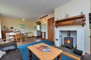 A cozy living room with a fireplace, wooden furniture, and a dining area. - Nant Y Mynydd (Amlwch)