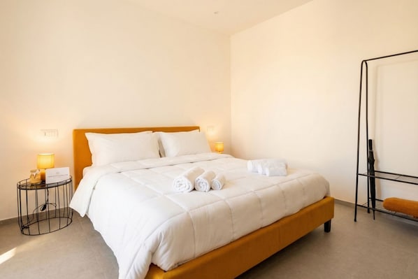 A hotel room with a bed, two bedside tables, a wall-mounted shelf, and a standing lamp. - Dimora dei Colori - Yellow Light (Bari)