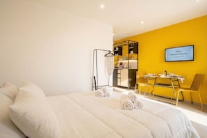 A hotel room with a bed, a desk, a chair, and a TV mounted on the wall.