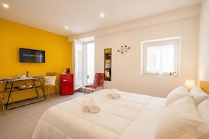A hotel room with a bed, a desk, a chair, a TV, and a window. - Dimora dei Colori - Yellow Light (Bari)