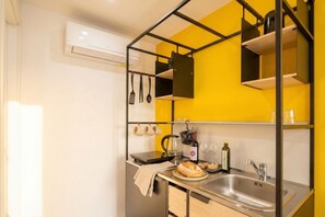 A compact kitchen with a sink, a countertop, and a hanging rack with utensils.