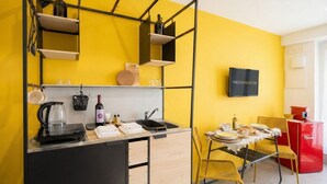 A compact kitchen with a black countertop, a wine bottle, and a kettle. - Dimora dei Colori - Yellow Light (Bari)