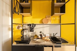 A compact kitchen with a yellow backsplash, a coffee maker, a kettle, a bread loaf, and a wine glass on the counter. - Dimora dei Colori - Yellow Light (Bari)