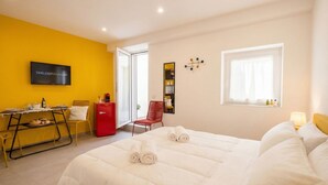Een hotelkamer met een bed, een bureau, een stoel, een televisie en een raam.