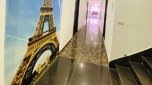 A hallway with a marble floor and a mural of the Eiffel Tower on the left wall. - Hotel Star Karnal (Karnal)