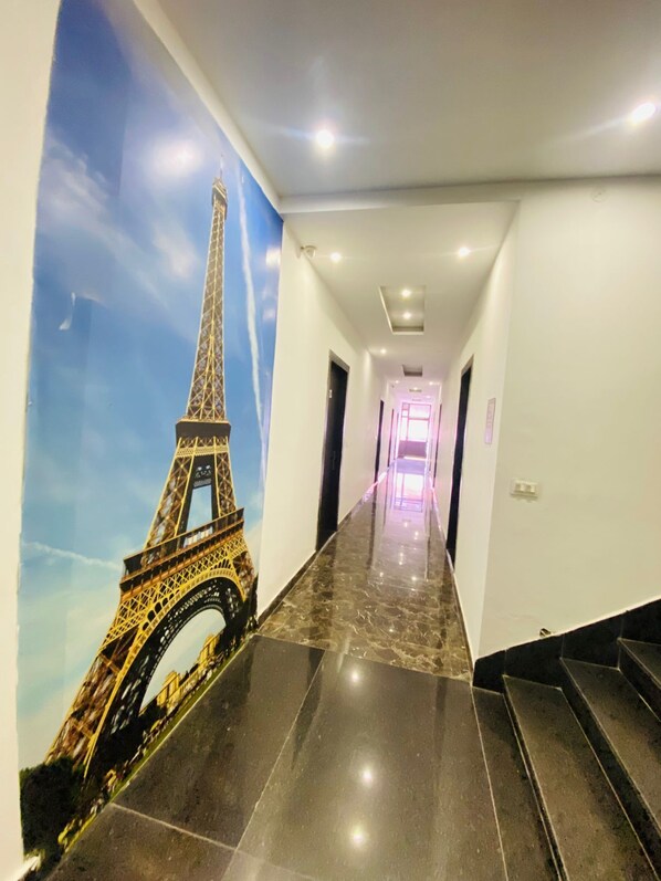 Un pasillo con suelo de mármol y un mural de la Torre Eiffel en la pared izquierda.