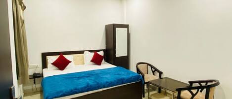 A hotel room with a bed, a desk, a chair, a ceiling fan, and a mirror.