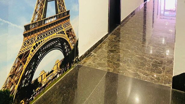 A hallway with a large mural of the Eiffel Tower, a polished marble floor, and a modern ceiling with recessed lighting. - Hotel Star Karnal (Karnal)