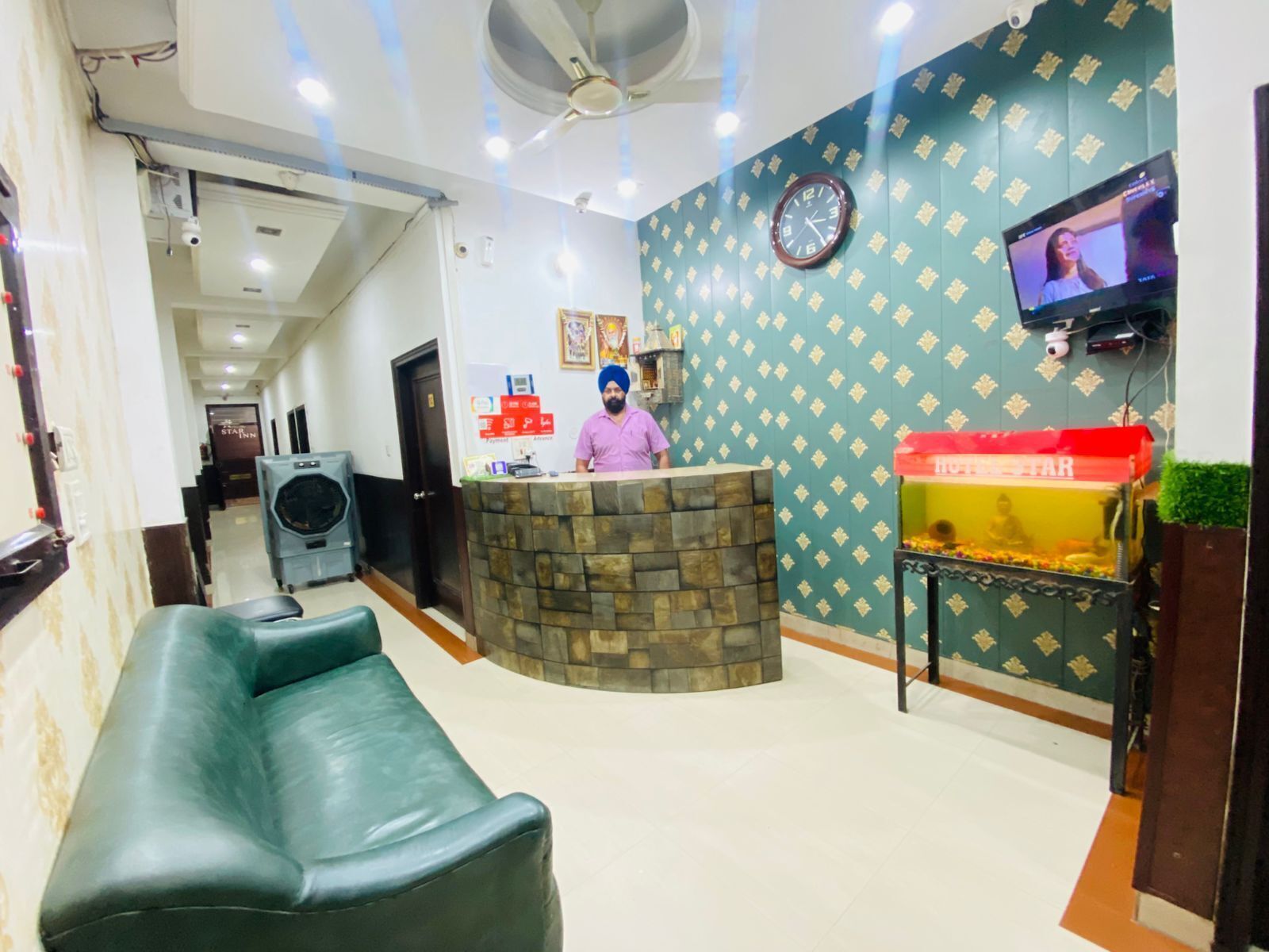 A reception area with a stone counter, a clock, a television, and a red box labeled "HOTEL STAR".