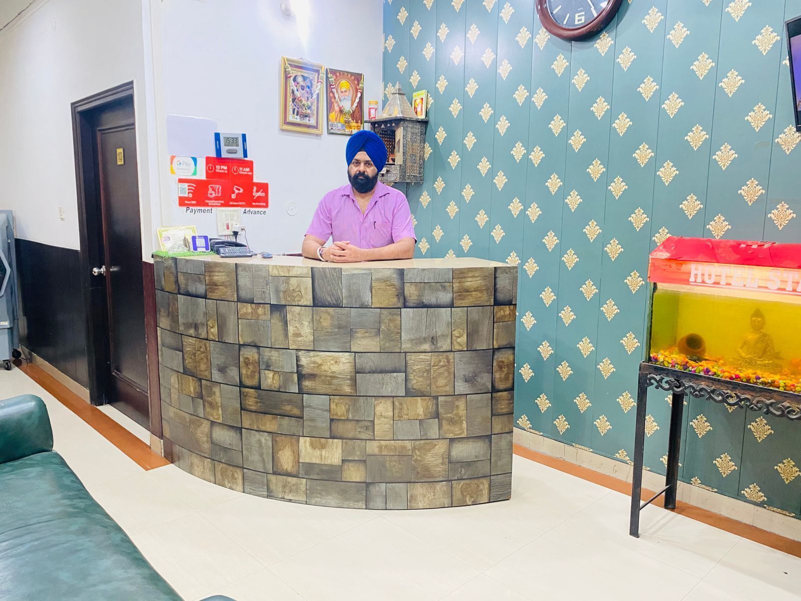 A reception desk with a stone facade, a clock on the wall, and a Buddha statue in a glass enclosure.