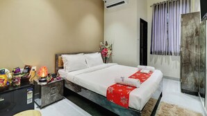 A hotel room with a bed, a nightstand, a desk, a shower, and a bathroom. - Royal Inn (Navi Mumbai)