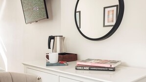 Een witte dressoir met een koffiepot, een mok en boeken.