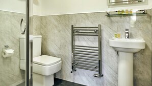 Une salle de bain comprenant des toilettes, une douche en verre, un porte-serviettes et un lavabo avec des articles de toilette.