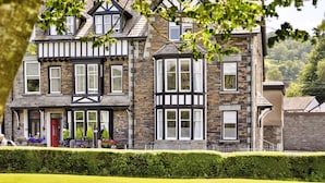 A large, multi-story house with a traditional architectural style, featuring a mix of stone and timber framing, multiple windows, and a well-maintained front garden. - Kelsick Villa Guest House - Great Gable (Ambleside)