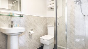A modern bathroom with a glass shower enclosure, a white sink, and a toilet. - Kelsick Villa Guest House - Wansfell (Ambleside)