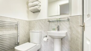 A bathroom with a toilet, a sink, a towel rack, and a glass shelf. - Kelsick Villa Guest House - Catbells (Ambleside)
