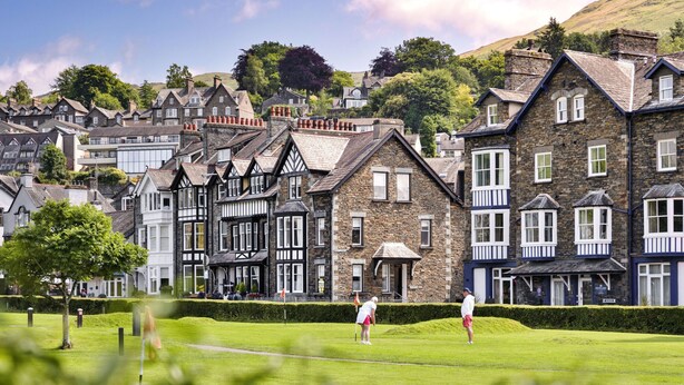 A golf course with traditional stone buildings in the background. - Kelsick Villa Guest House - Catbells (Ambleside)