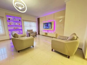 A modern living room with two beige sofas, a flat-screen TV, and a built-in shelf with decorative items.