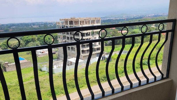Un balcone con ringhiera metallica che si affaccia su un cantiere e un paesaggio verde.