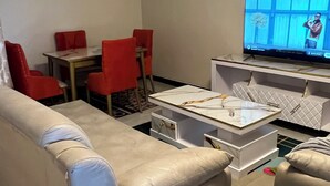 Un soggiorno moderno con un divano beige, un tavolino da caffè e una TV su un mobile.