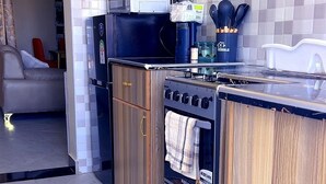 Una cucina compatta con mobili in legno, forno integrato e forno a microonde. Due sottopiatti intrecciati sul pavimento.
