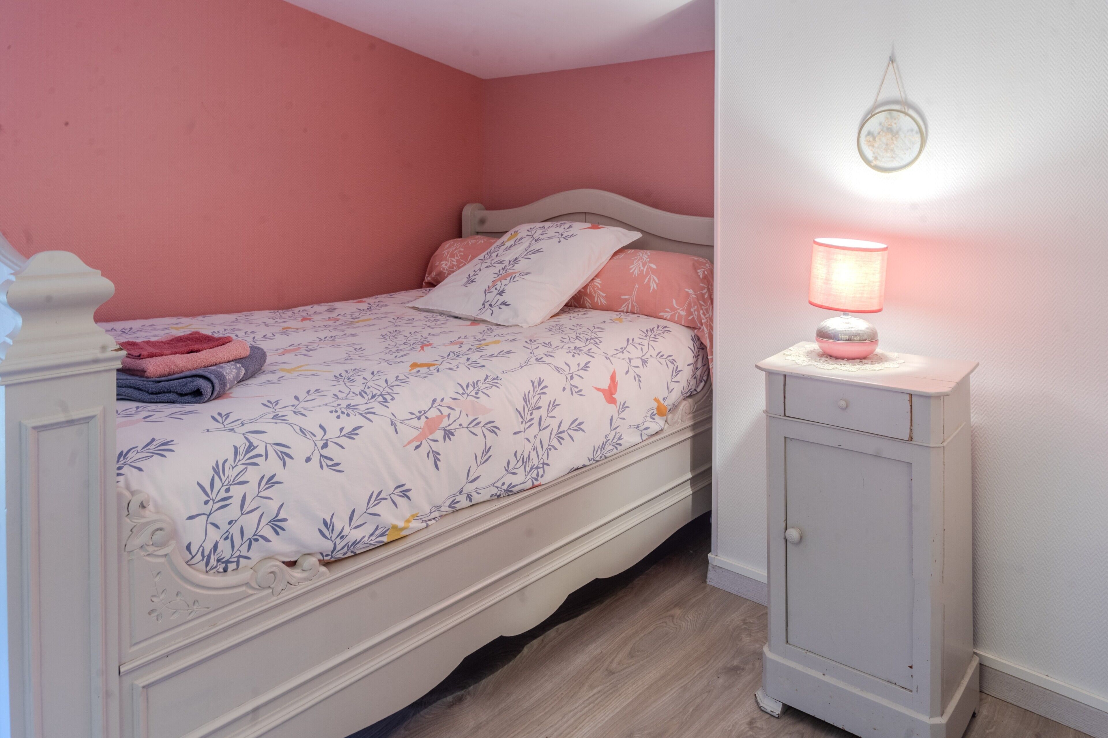 A bedroom with a bed, a bedside table with a lamp, and a wardrobe.