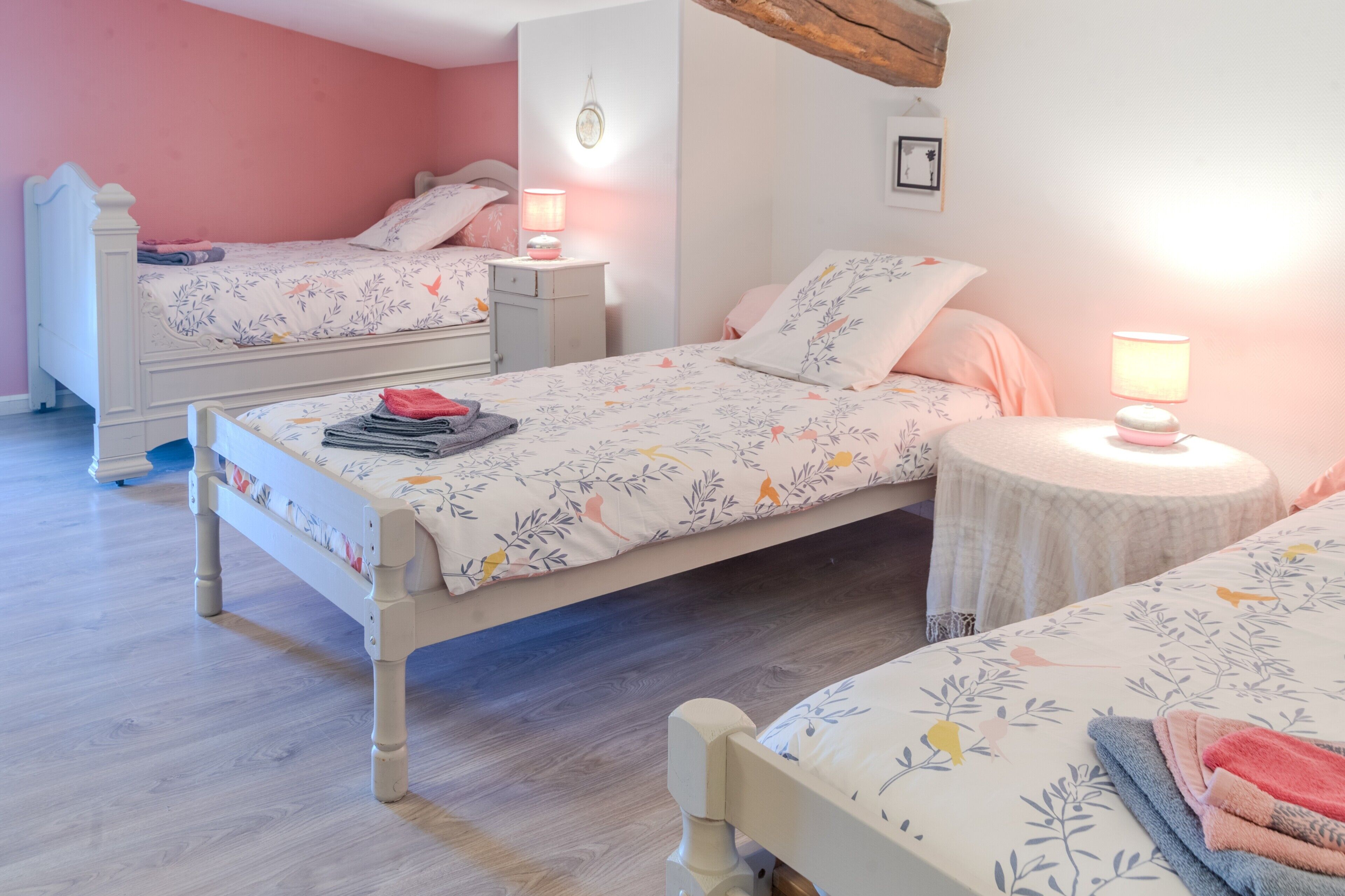 Une chambre avec deux lits, une petite table ronde et une table de chevet avec une lampe.