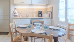 A dining area with a round table set for four, equipped with plates, glasses, and cutlery. - Le logis chez bompain (Brizambourg)